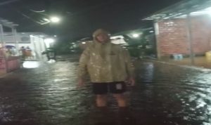 Seorang Warga berdiri diatas genangan banjir tepatnya di Tanjung Baranagan, Kota Palembang. Foto : Ist