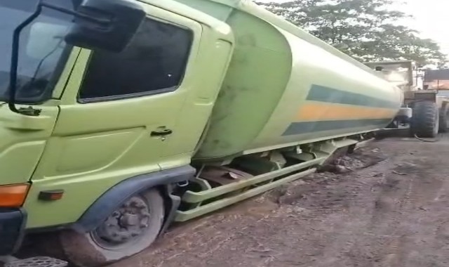 Sebuah truk tangki besar amblas dan miring di tengah jalan akibat permukaan tanah yang lembek dan berlumpur pekat. Foto : Nto/red