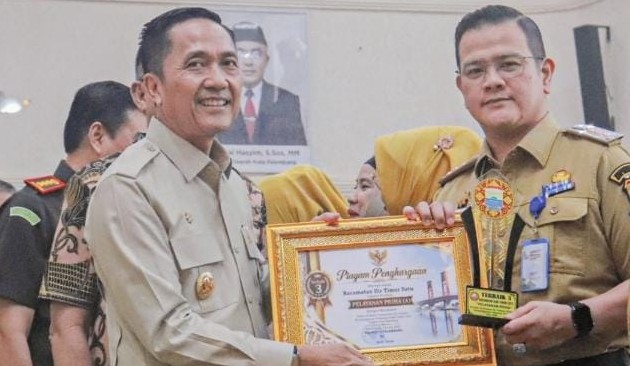Wali Kota Palembang Ratu Dewa saat menyerahkan Penghargaan kepada Camat Ilir Timur I Purba Sanjaya. Foto : Is